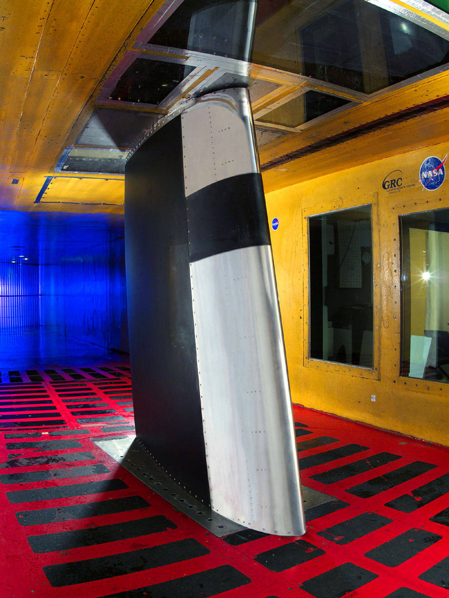 Inside bright yellow wind tunnel with aircraft fin in center and red floor