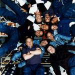 Ten astronauts and cosmonauts pose in circle inside Spacelab module