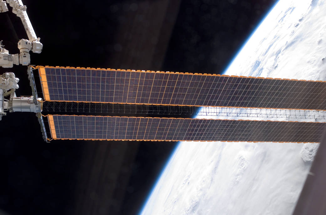 Solar array of International Space Station with space and curve of Earth visible in background