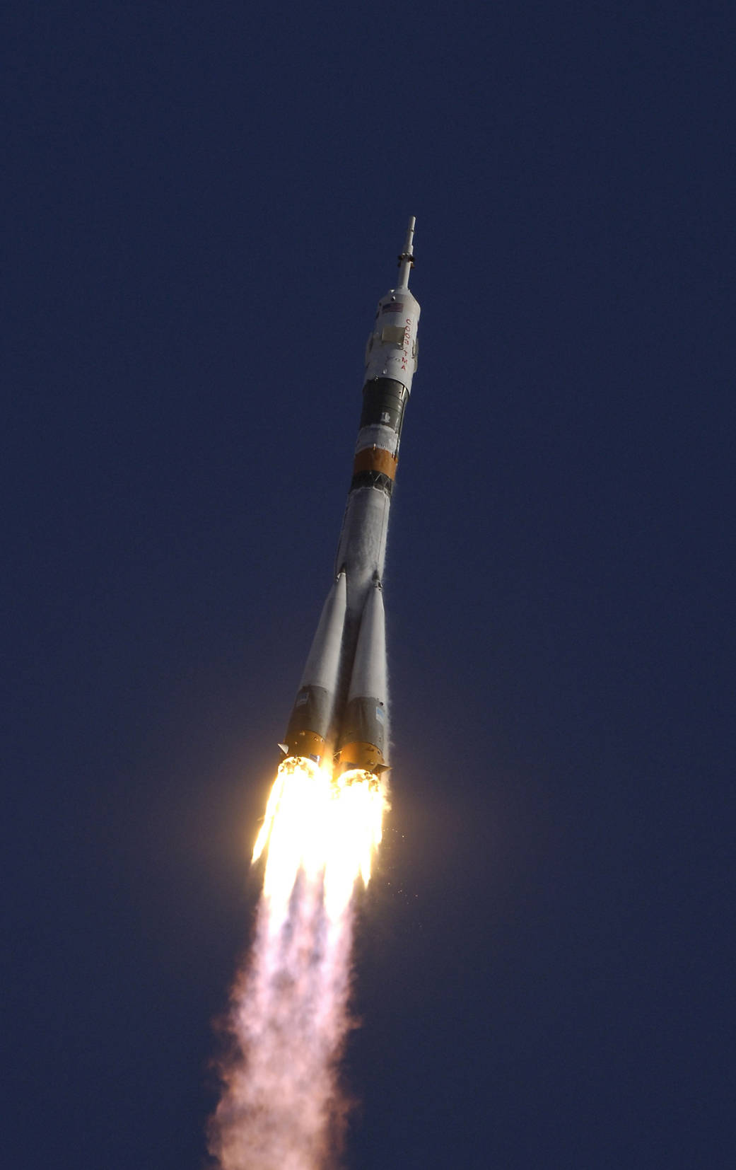 Soyuz rocket just after launch headed diagonally upward into blue sky