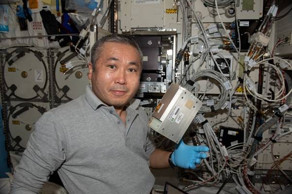image of an astronaut holding up experiment hardware