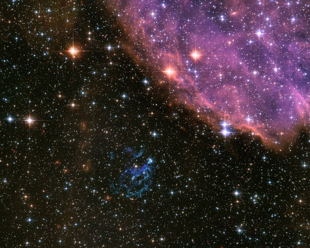 Cloudy pink remnant of supernova in upper right with stars of varying brightness