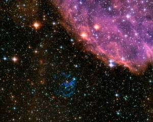 Cloudy pink remnant of supernova in upper right with stars of varying brightness