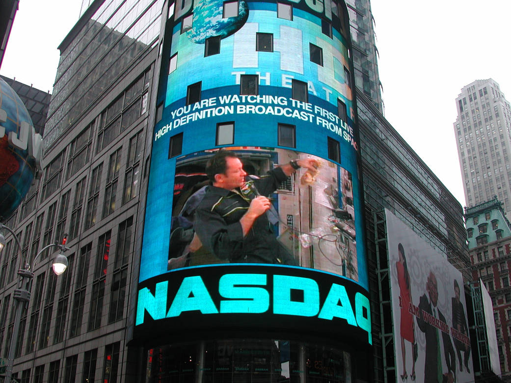 Large screen on rounded corner of New York building displaying astronaut speaking into microphone and NASDAQ letters below