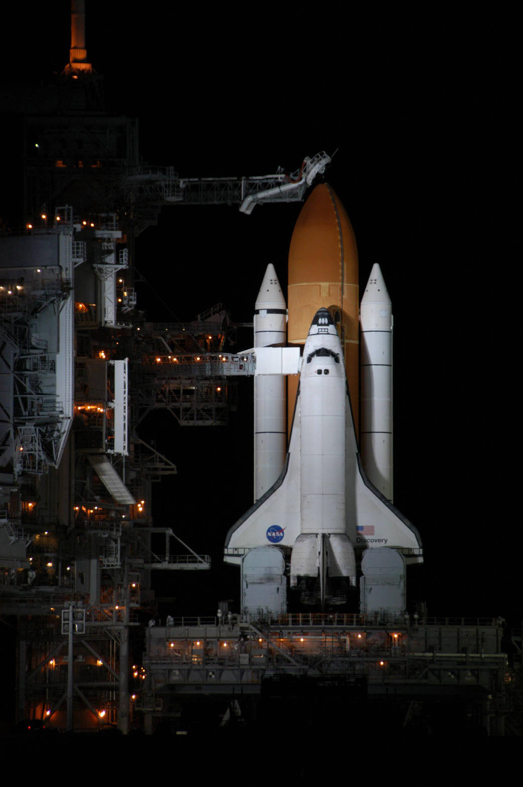 Shuttle Discovery vertical on launch pad at night