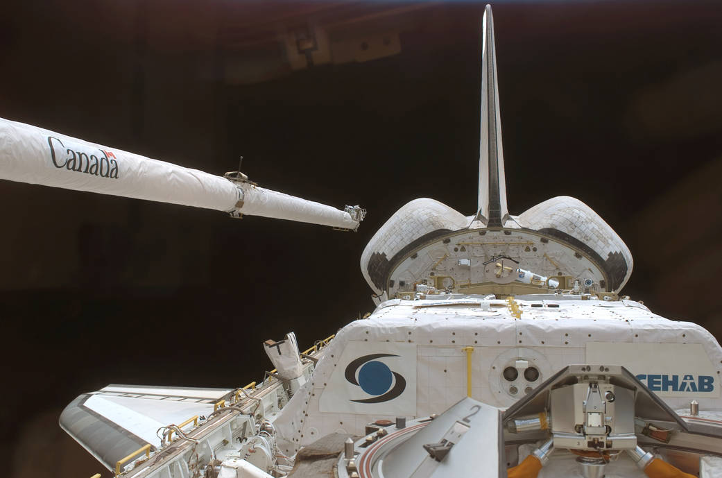 Tail and robotic arm of shuttle Discovery in orbit