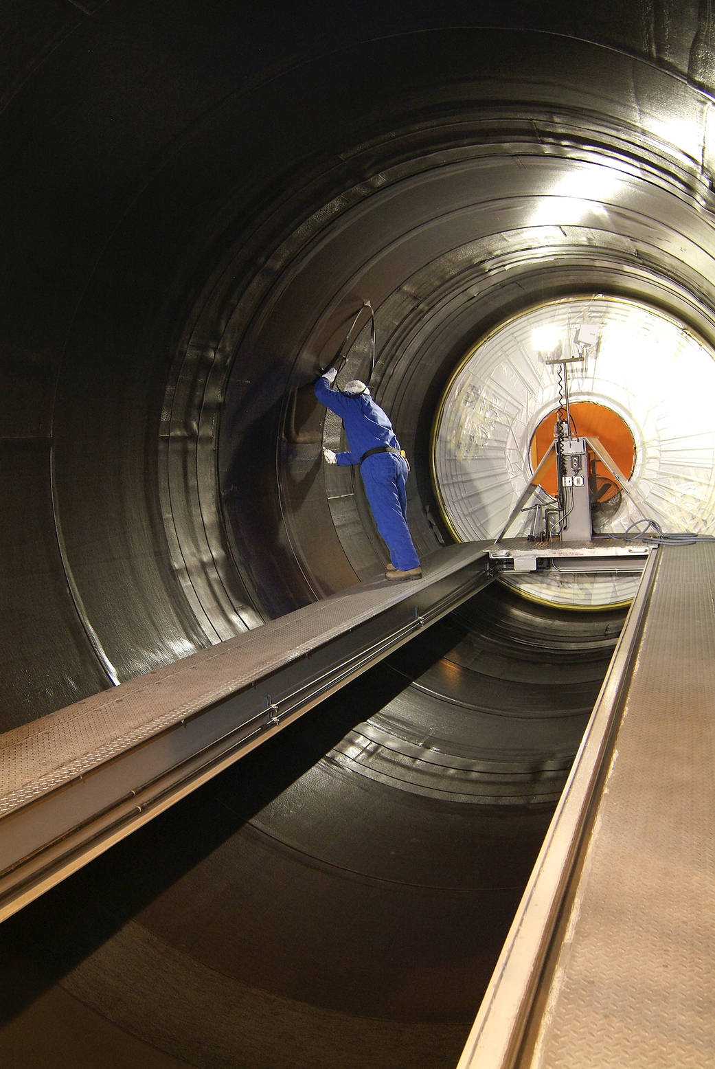 An ATK technician installs one of more than 900 plies of insulation onto the inner diameter of an SLS booster segment case. 