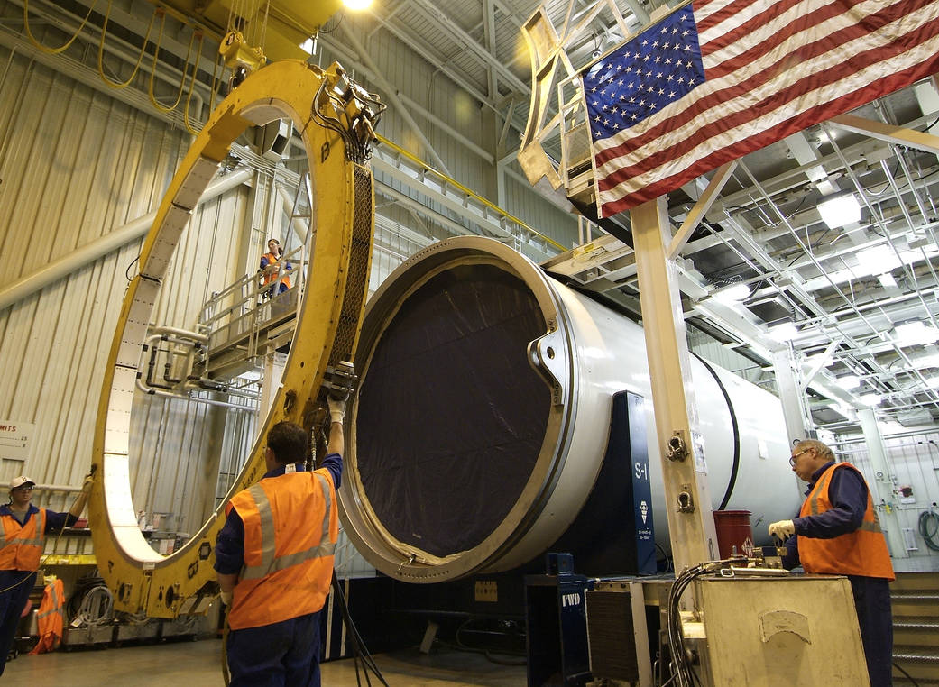 Technicians remove a rounding fixture from the solid rocket motor center segment. 