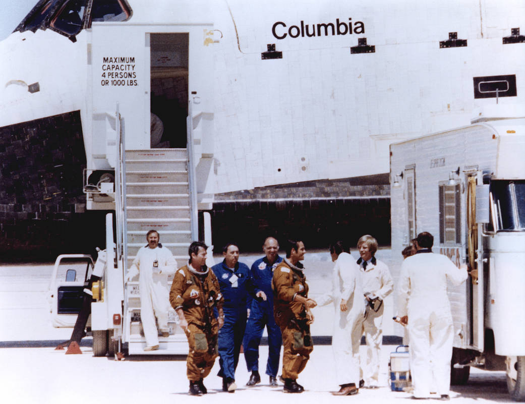 Astronauts in tan space suits are greeted by members of the ground crew after stepping off the shuttle Columbia