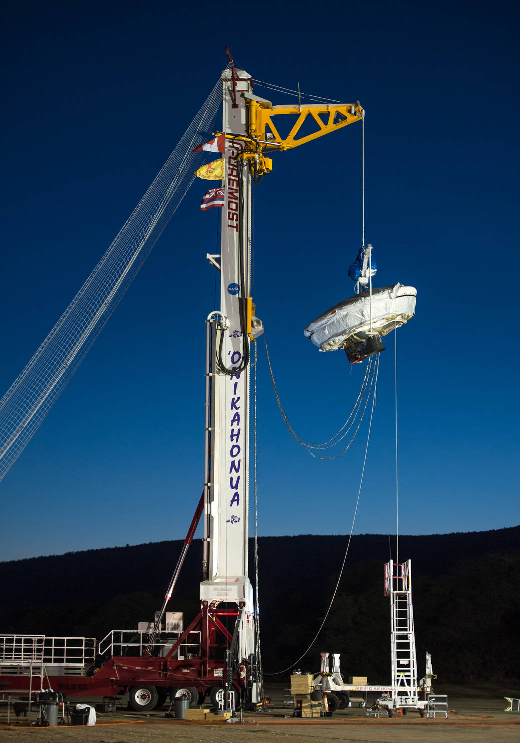 LDSD saucer shaped vehicle hangs suspended from test rig against night sky