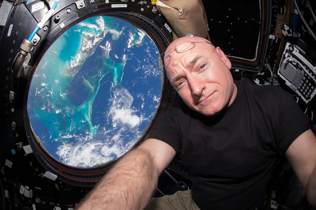 NASA astronaut Scott Kelly in the Cupola of the International Space Station with blue water of Earth visible through window