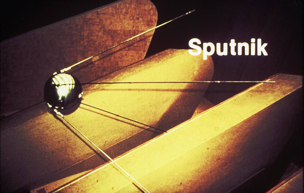 Round, silver Sputnik satellite against yellow background