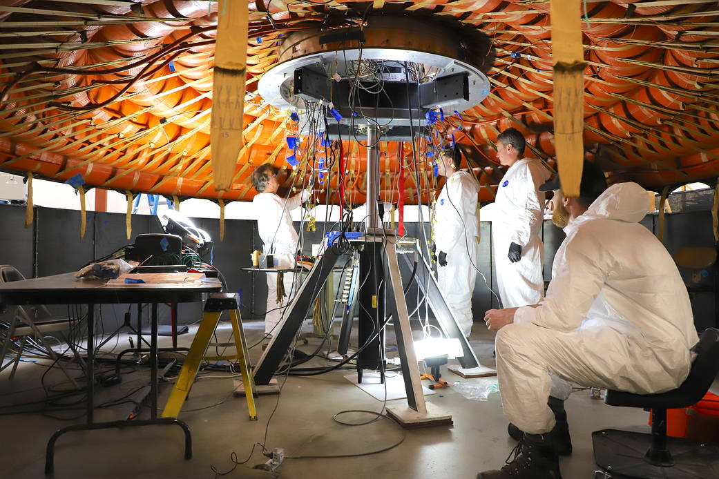 People working with heat shield inflatable structure.