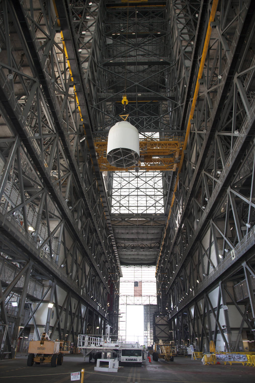 In the transfer aisle of the Vehicle Assembly Building at NASA’s Kennedy Space Center in Florida, a crane operator lifts a ful