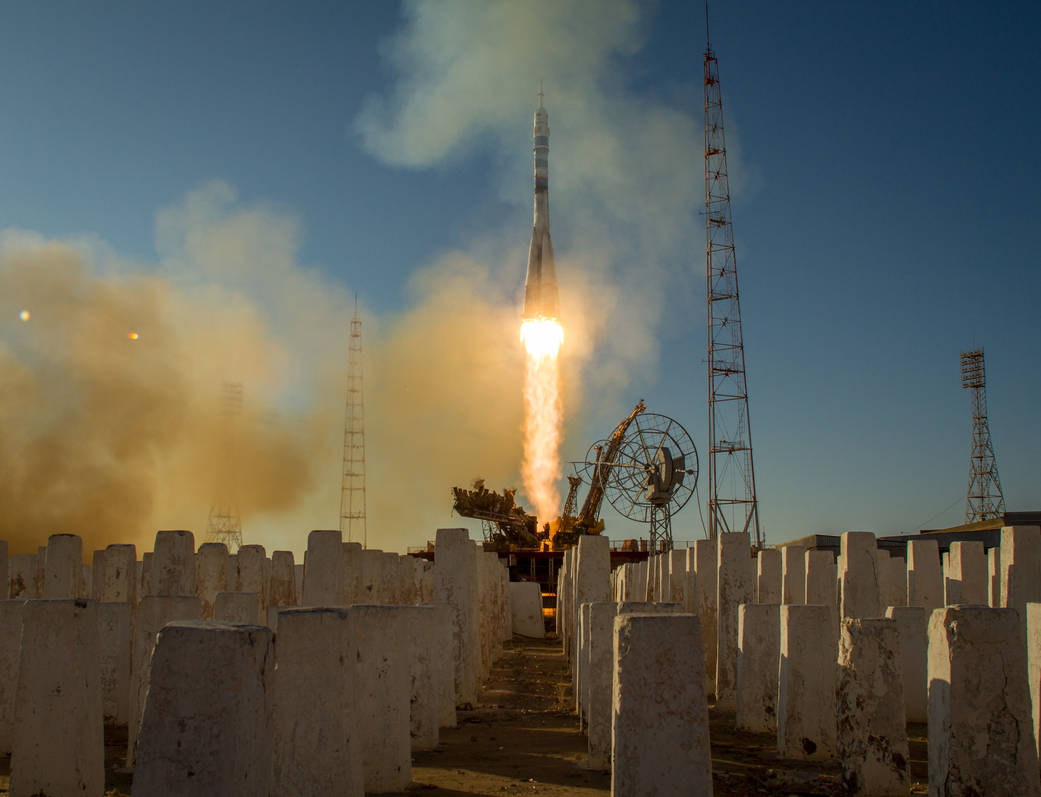 Daytime launch of Soyuz rocket with rows of concrete planks in foreground