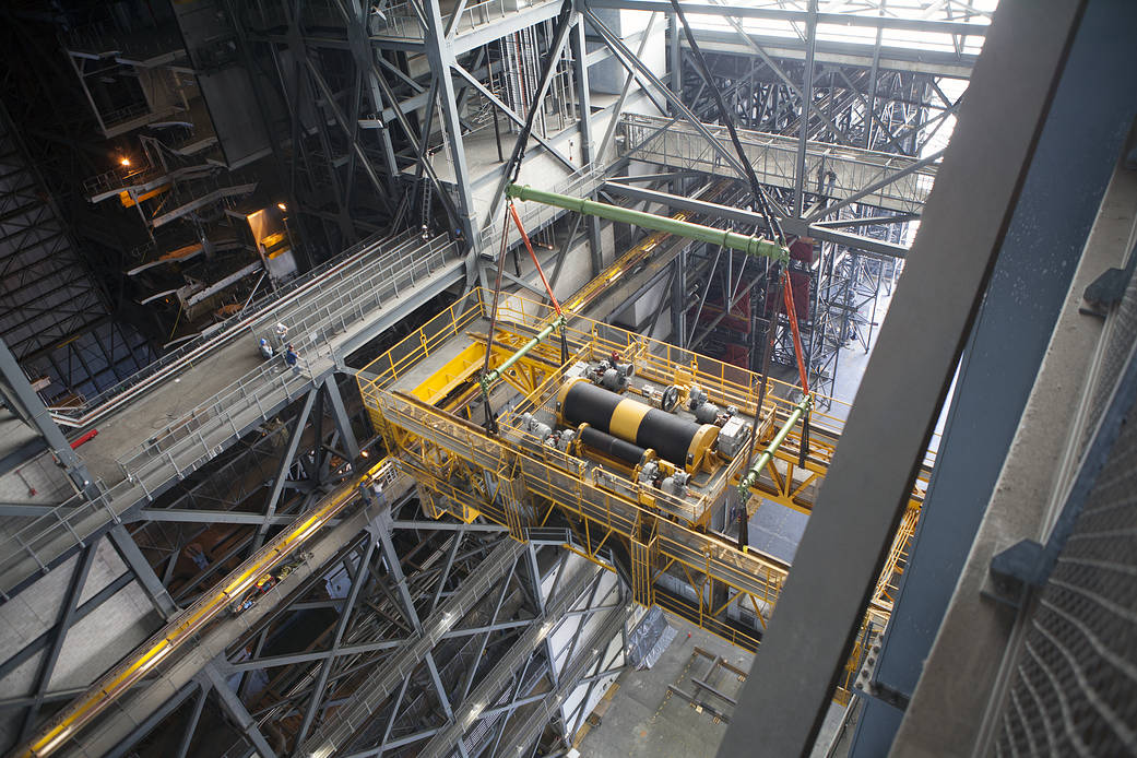 A view from above shows a crane being used to lower the 175-ton crane inside the Vehicle Assembly Building