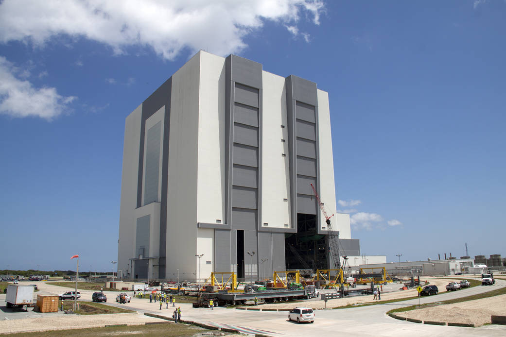A flatbed truck carries the first half of a new set of work platforms to the Vehicle Assembly Building