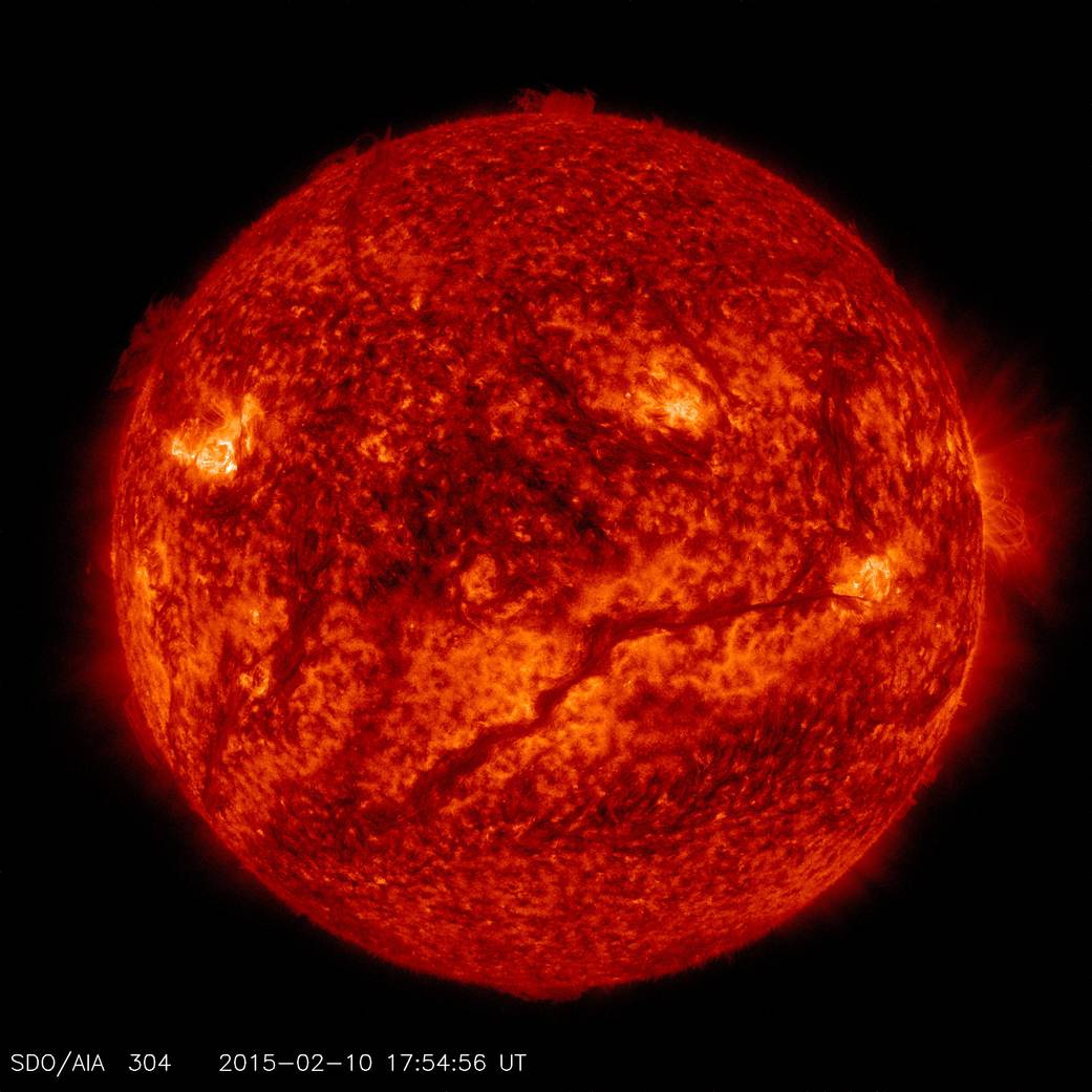 A dark, snaking filament hovers above the sun's lower hemisphere.