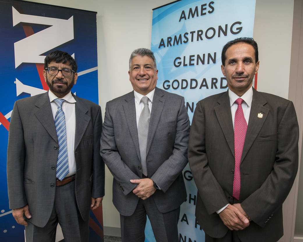 Three individuals in front of two NASA banners.