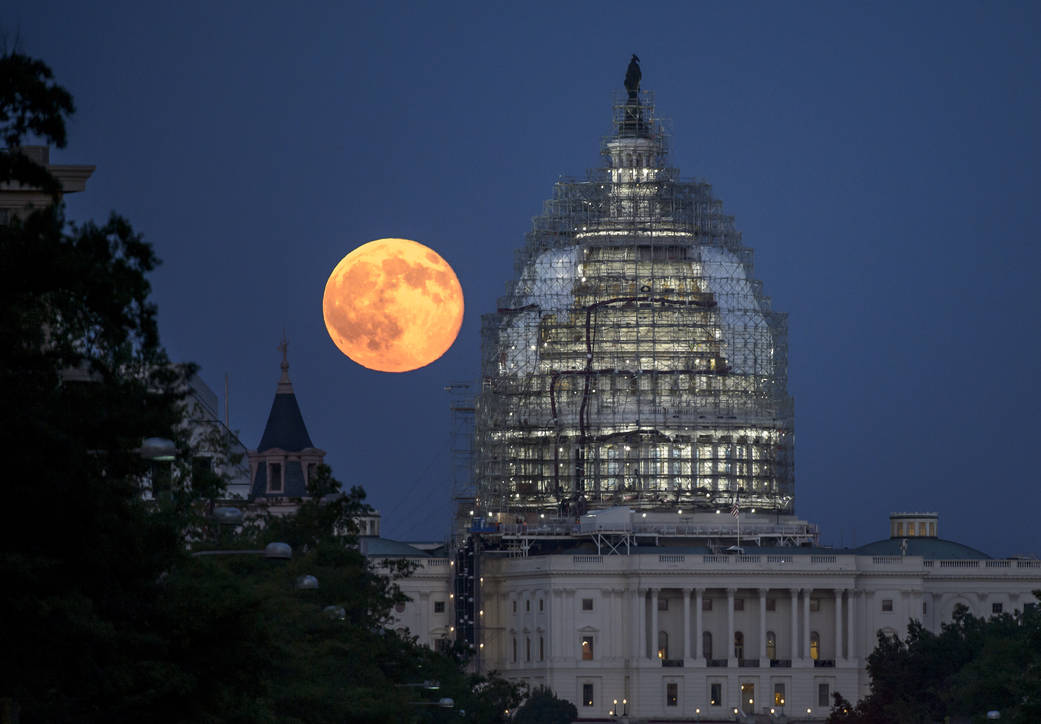 A second full moon for the month of July is seen next to the dome of the U.S. Capitol on Friday, July 31, 2015.