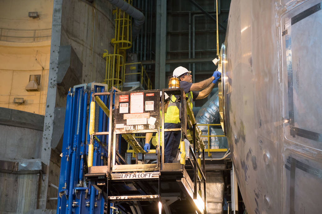 Todd Gough installs the end cap test fixture on a weld confidence article of the liquid oxygen tank for NASA's new rocket