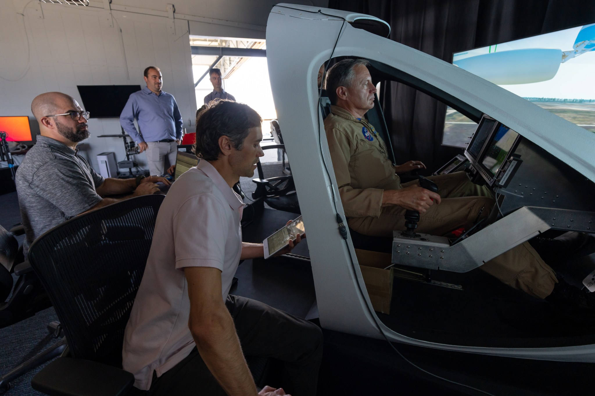 Federal Aviation Administration Unmanned Aircraft System Integration Office program manager Brad Drake, left, tracks flight path data as NASA project operations engineer Andrew Guion provides formulas to NASA research pilot Wayne Ringelberg Sept.19 in Marina, California. In the background, Joby Aviation’s Ryan Naru and NASA partner demonstration lead Gerrit Everson observe the work in the Joby S4 simulator.