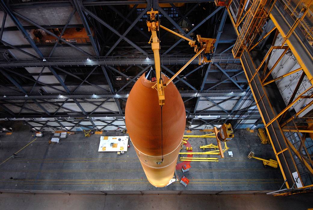 Inside the Vehicle Assembly Building at NASA's Kennedy Space Center in Florida, the external tank for space shuttle Discovery's mission STS-124 is suspended over the transfer aisle as it is lifted up into a checkout cell for processing.