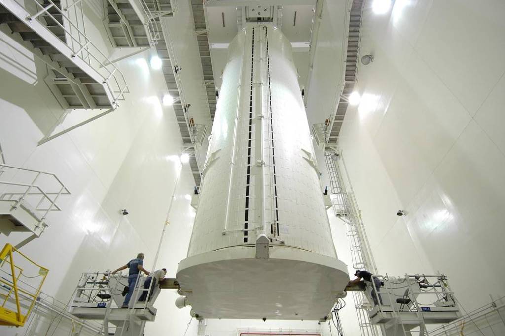 In the Vertical Integration Facility at NASA's Kennedy Space Center in Florida, workers on either side of the payload canister check its condition after it was rotated from a horizontal position. 
