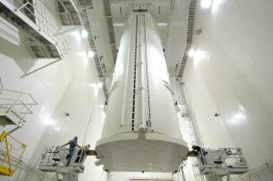 In the Vertical Integration Facility at NASA's Kennedy Space Center in Florida, workers on either side of the payload canister check its condition after it was rotated from a horizontal position.