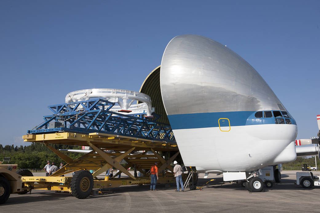 Orion service module secured to platform with open front of Super Guppy aircraft at left