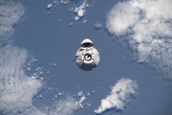 image of a capsule approaching the space station with the Earth in the background