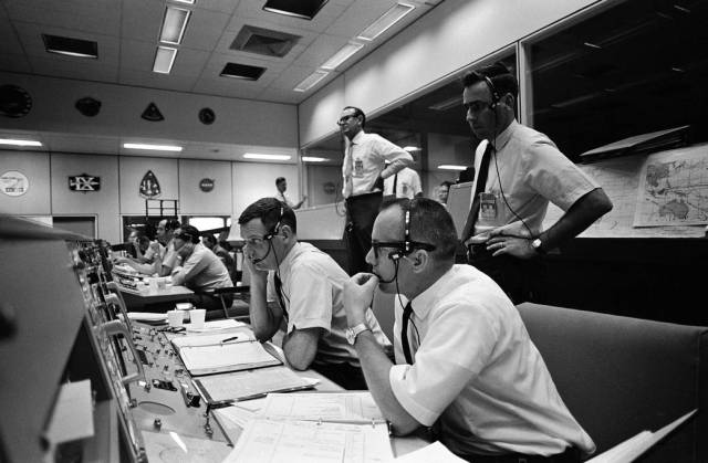 Black and white photo of Mission Operations Control Room with flight directors seated