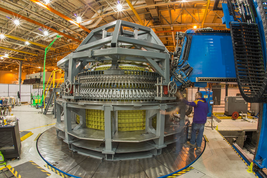 Orion spacecraft structure inside large room with engineer standing at right