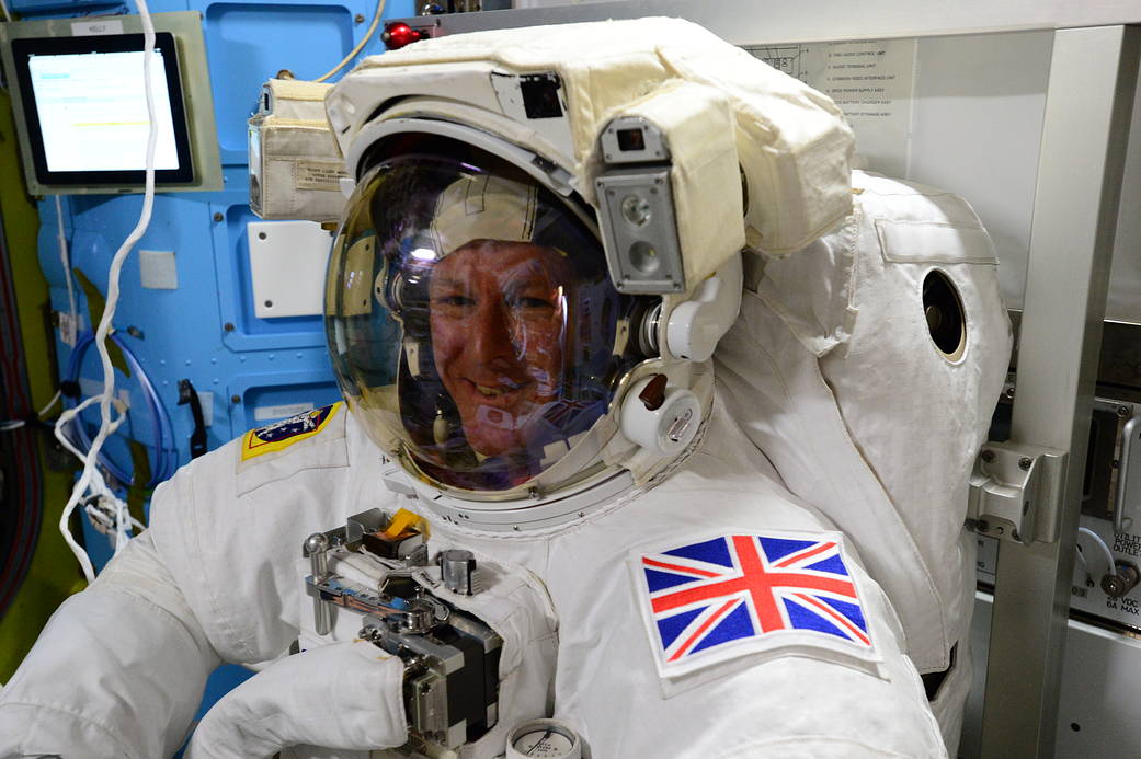 ESA astronaut Tim Peake inside International Space Station wearing spacesuit with UK flag patch on arm