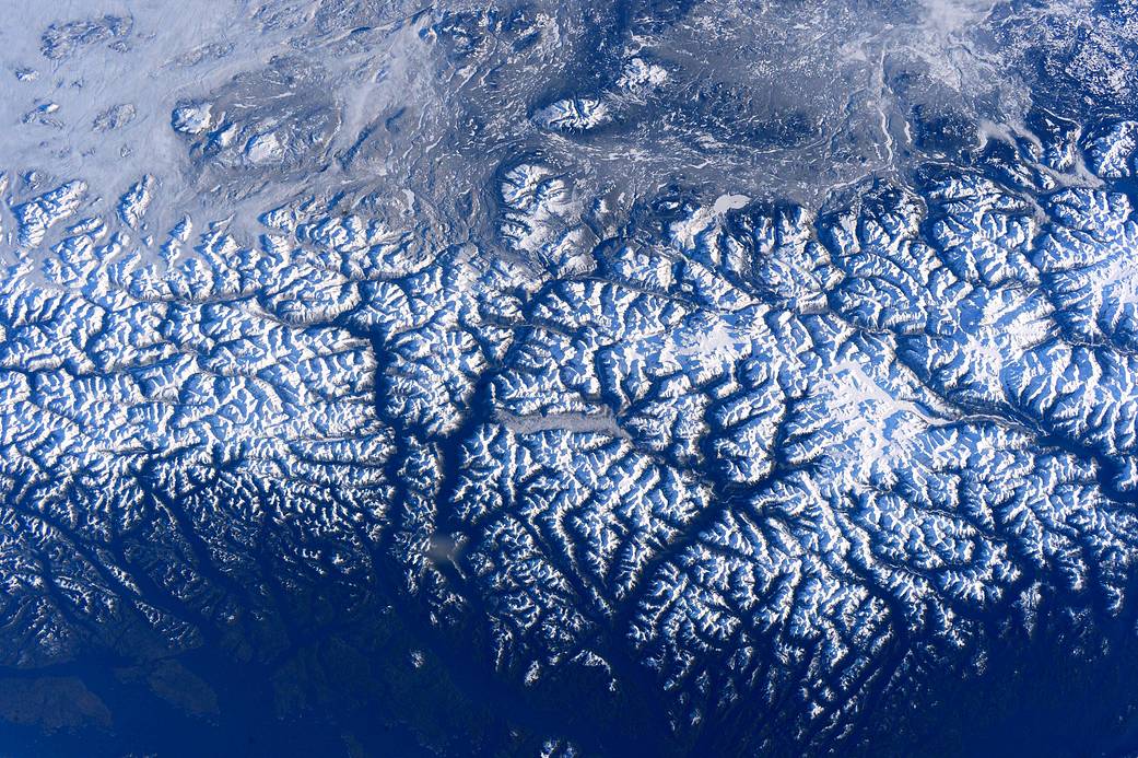 Snowcapped rocky mountain range on the coast photographed from orbit