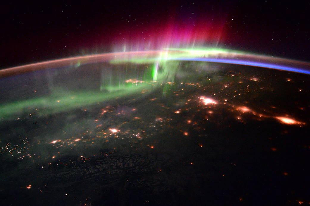 Bright lights of an aurora and city lights on Earth photographed from low Earth orbit