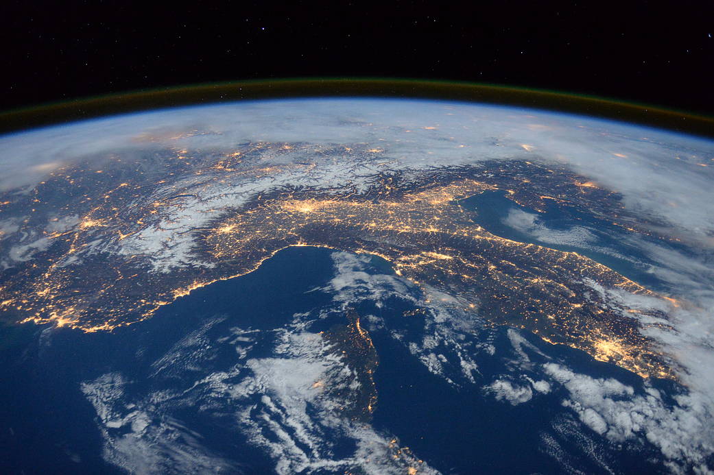 Nighttime photograph from low Earth orbit of Mediterranean showing clouds and city lights