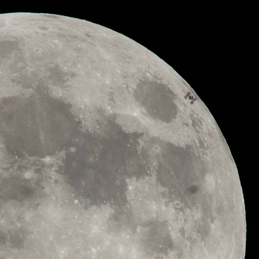 The International Space Station, with a crew of six onboard, is seen in silhouette as it transits the moon at roughly five miles