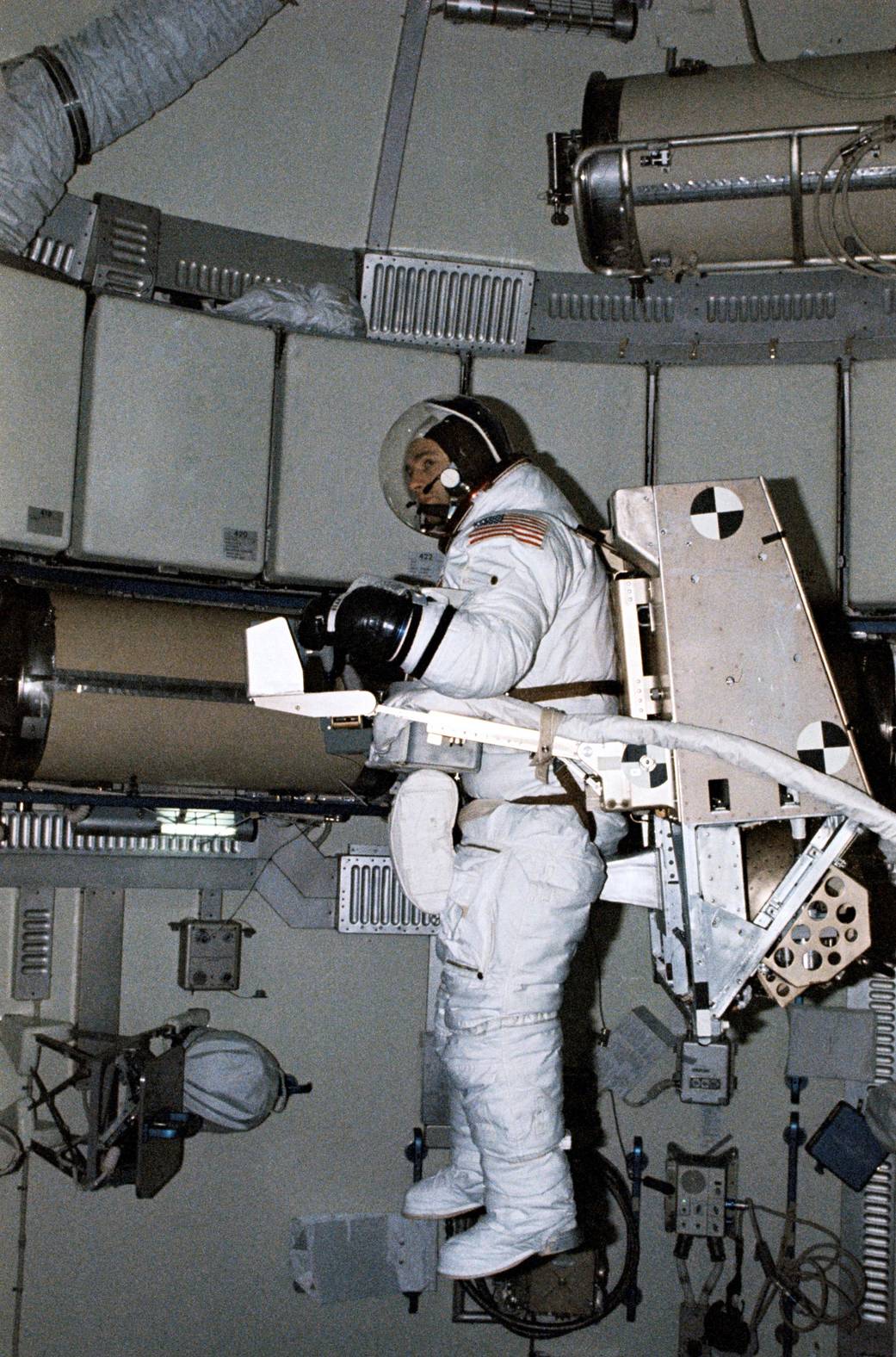 Astronaut wearing pressure suit working on experiment inside Skylab 