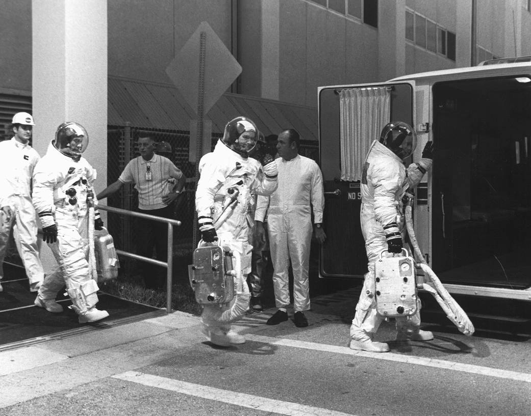 Apollo 11 astronauts in spacesuits walking through a room at Kennedy Space Center