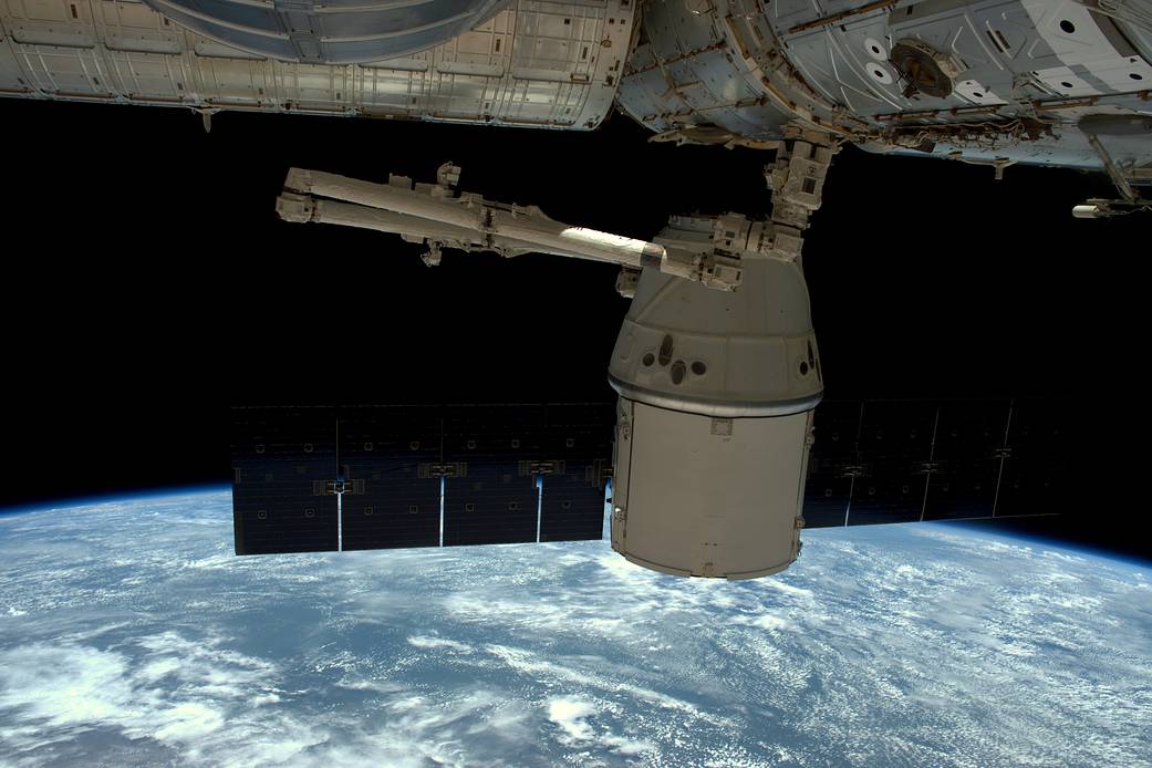 Dragon spacecraft undocking from space station with Earth visible below