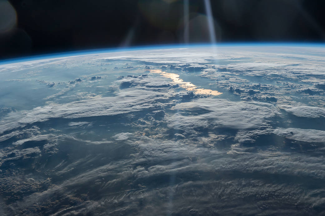 Clouds and golden sun glint photographed from low Earth orbit