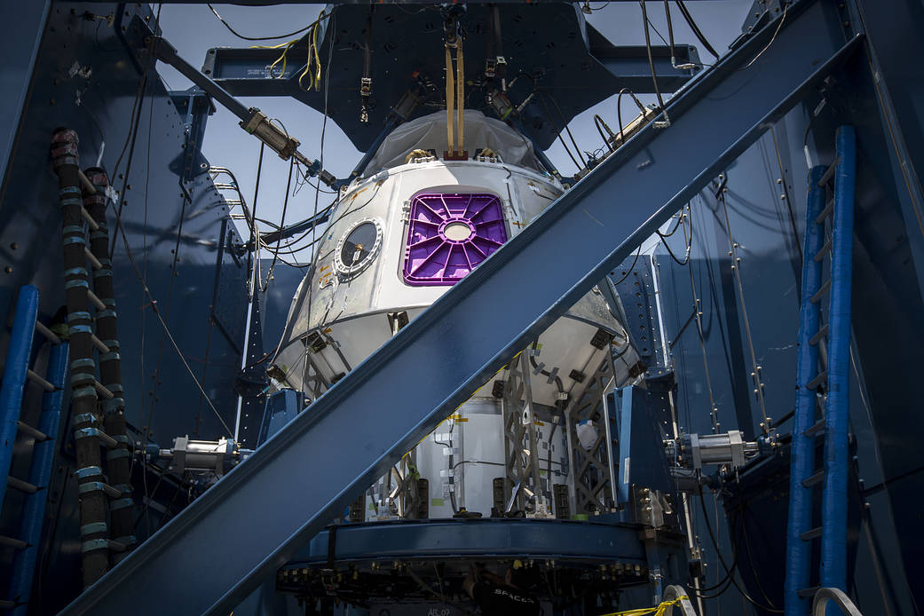 SpaceX Crew Dragon test article inside room surrounded by metal structure