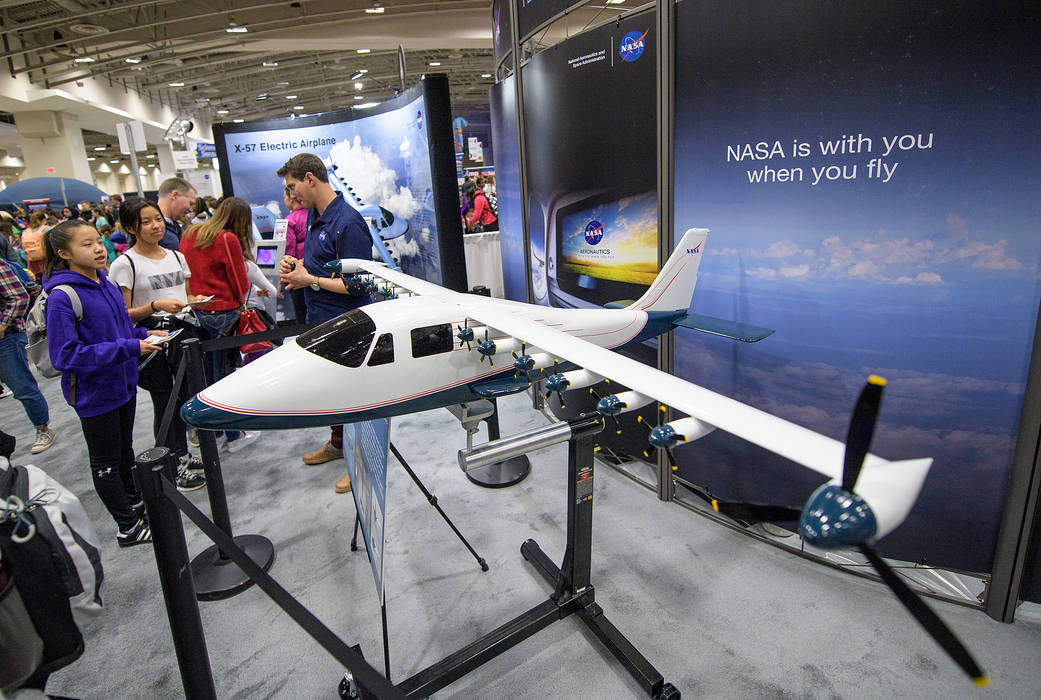 Attendees listen to a NASA staff member speak about the X-57