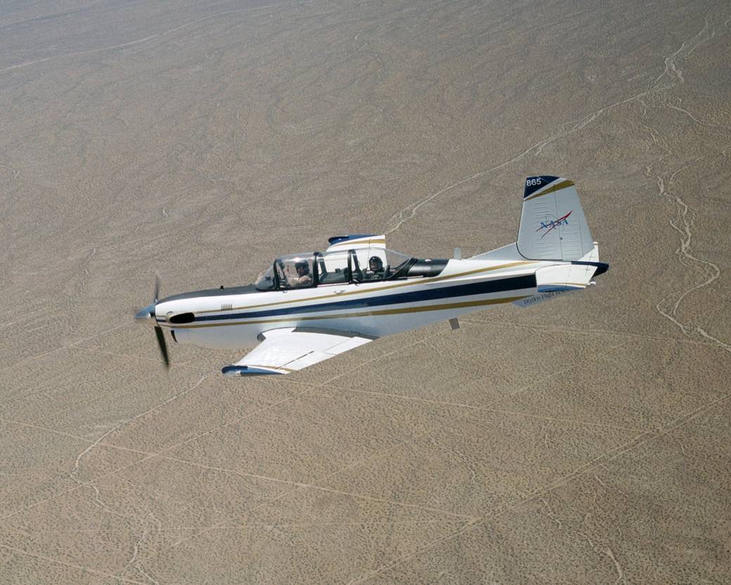 T-34C is seen in flight with desert floor below.