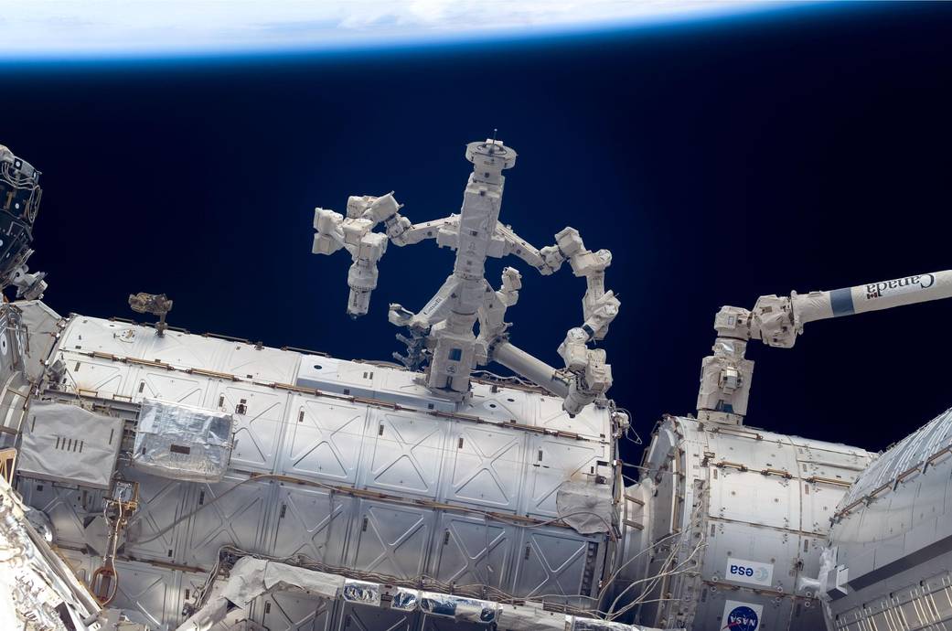 Dextre robotic arm outside International Space Station with Earth horizon in background