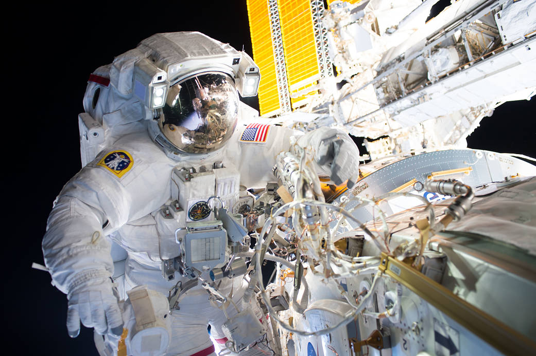 Astronaut in spacesuit working outside space station with solar array in background