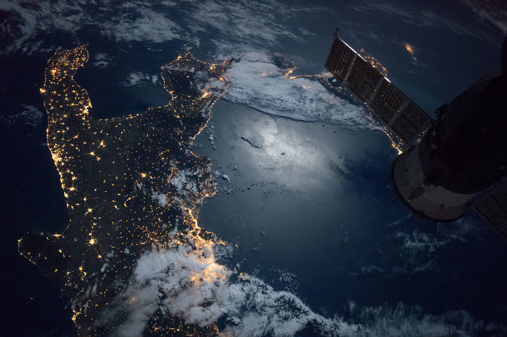 Nighttime view of southern Italy with glint on water from moonlight, taken from low Earth orbit