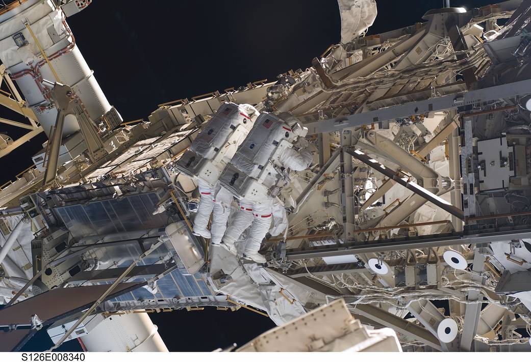 Two spacewalkers working side by side outside International Space Station