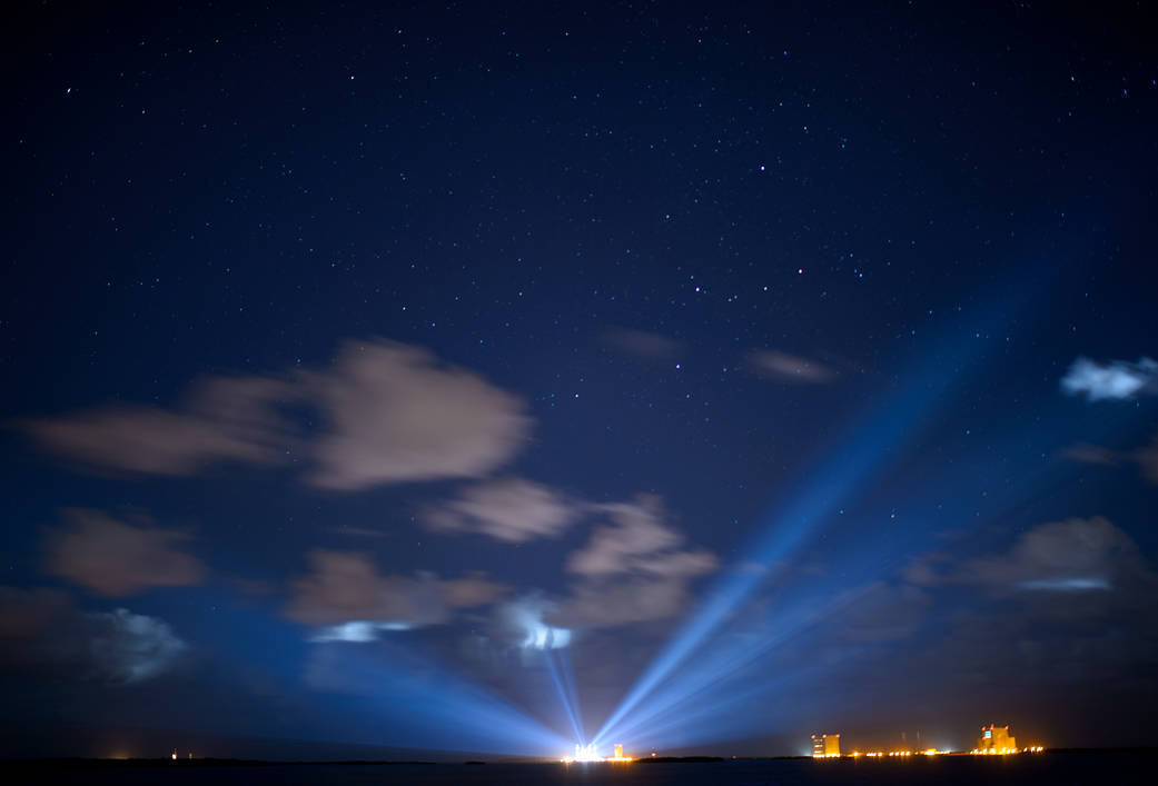 ULA rocket with OSIRIS-REx spacecraft at launch pad in the distance at nighttime